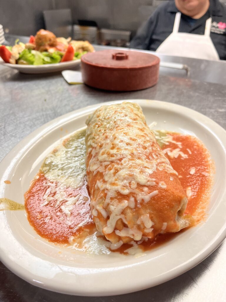 Combination number 2, chicken burrito served enchiladas style with both red sauce, green sauce, and cheese on top.